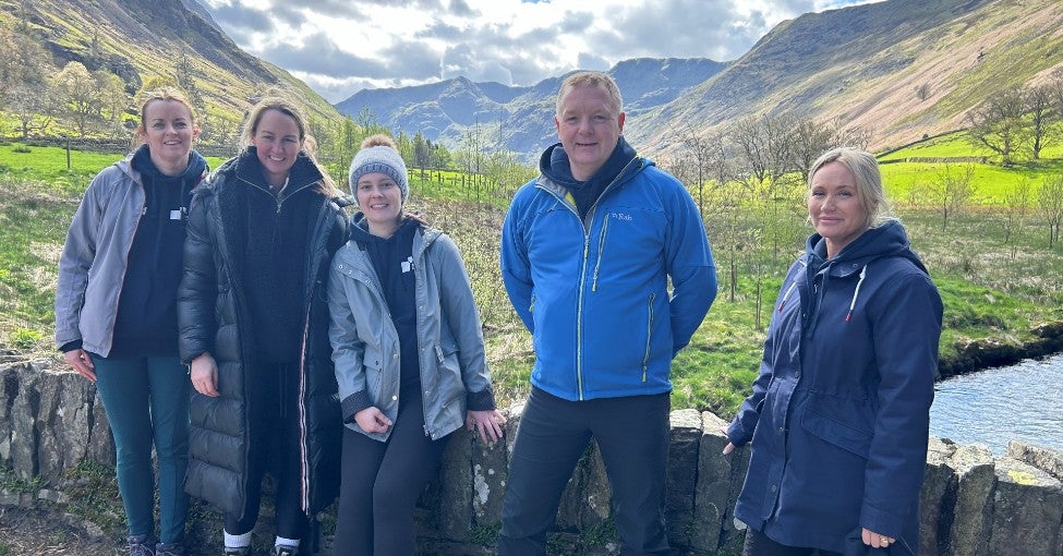A group of people out in the countryside with some hills in the background. 
