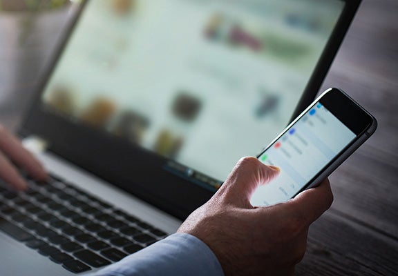 A man using a laptop and mobile phone. 