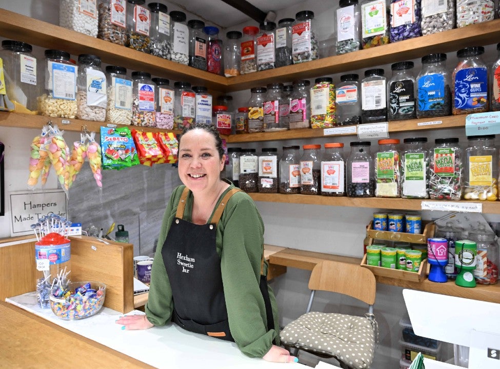 A woman standing behind a counter in a shop.
