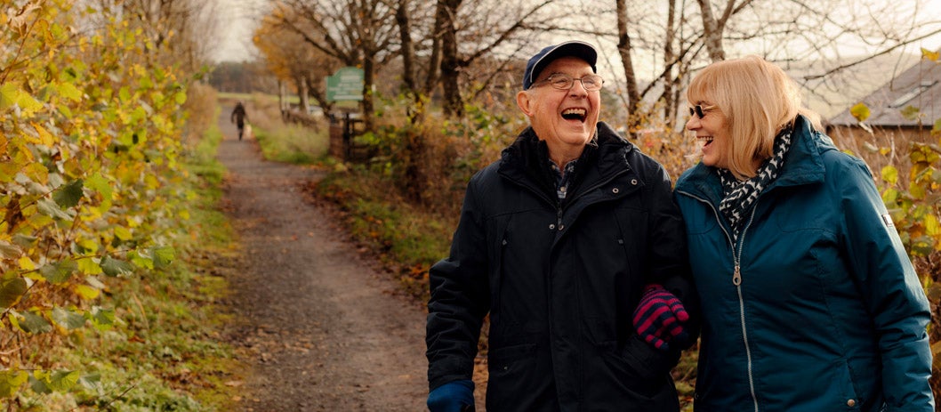 A man and a woman laughing on a country lane
