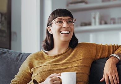 A happy woman relaxing on a sofa while having a cup of coffee