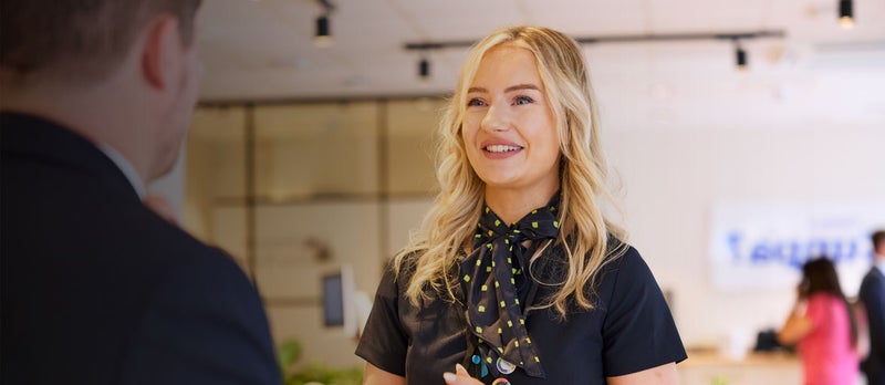 A Newcastle Building Society employee, working in the branch, smiling with a customer. 