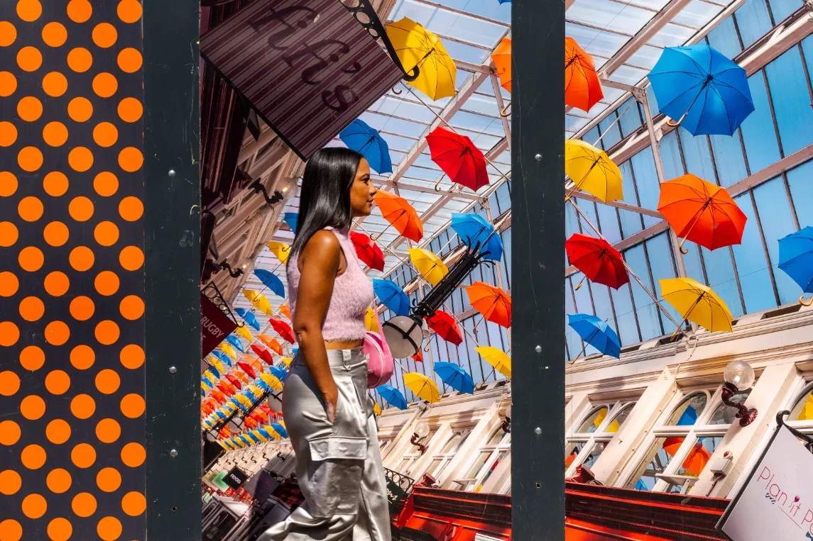 A woman walking in a room in Wigan with colorful umbrellas