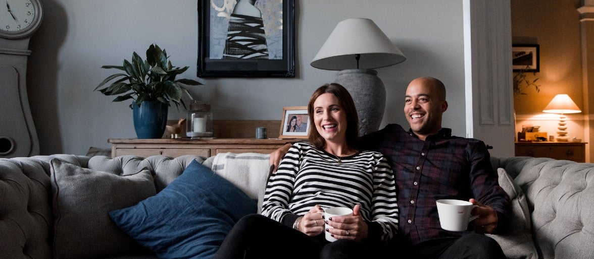 A couple, comprising a man and a woman, sitting on sofa