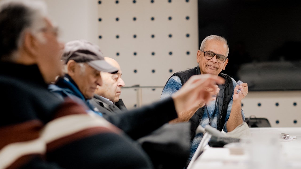 A group of men sat around a table chatting with each other.