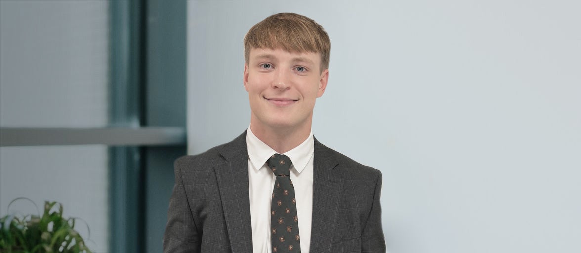Newcastle Financial Adviser, Alex Ford, stood smiling with a suit on. 