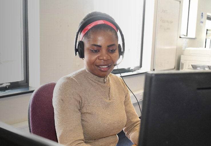 Lady sat at a computer desk with headphones on looking at a desktop computer