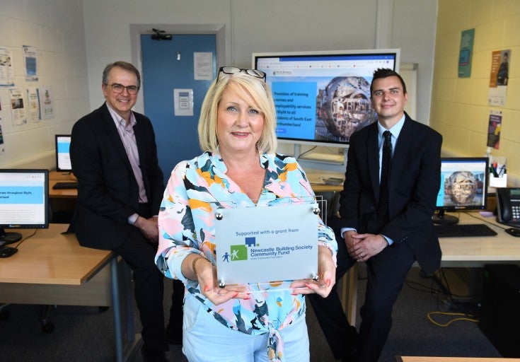 Three people with a community grant plaque
