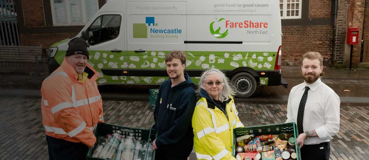 Members of FareShare and Newcastle Building Society stood in front of their food transportation van holding crates of food. 