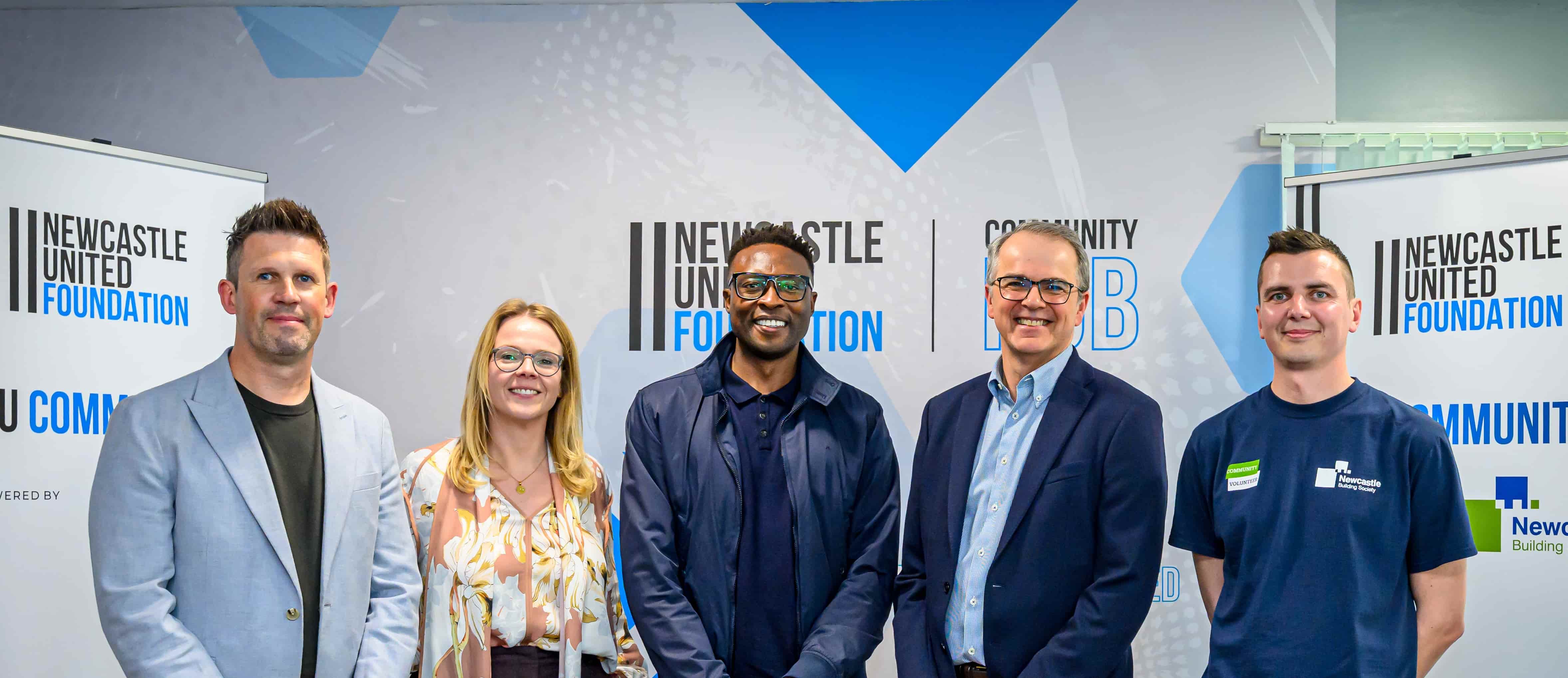 Andrew, Jill and Stephen from Newcastle Building Society with Shola Ameobi, stood in front of Newcastle United Foundation banner stands 