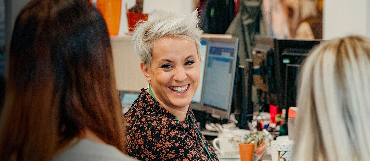 A colleague smiles at two others