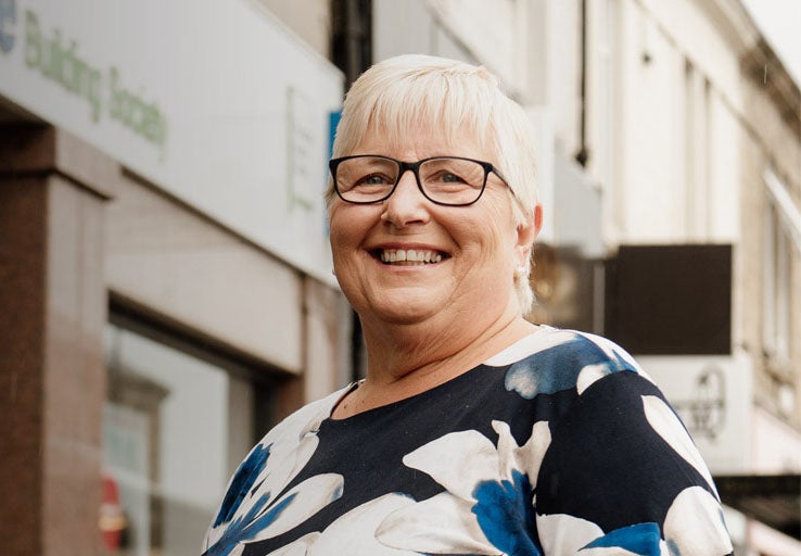 An older lady with short hair, smiling outside Gosforth branch.