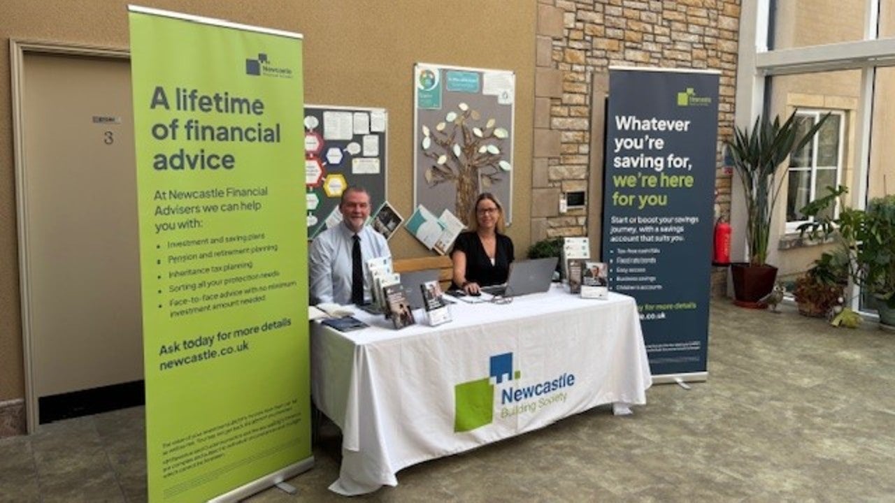 A man and woman sitting at a table with a laptop.