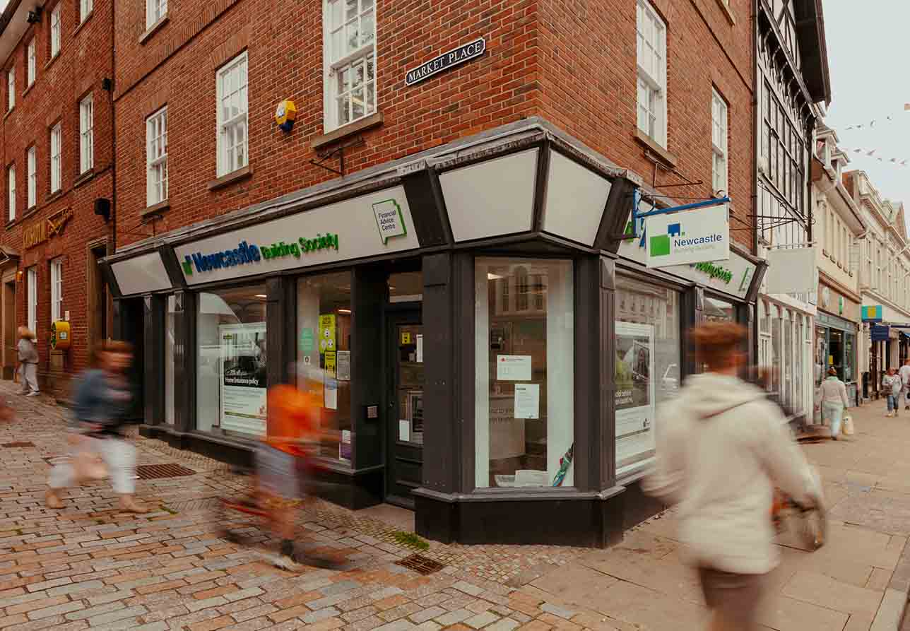 Exterior of Morpeth branch with out of focus shoppers walking past. 
