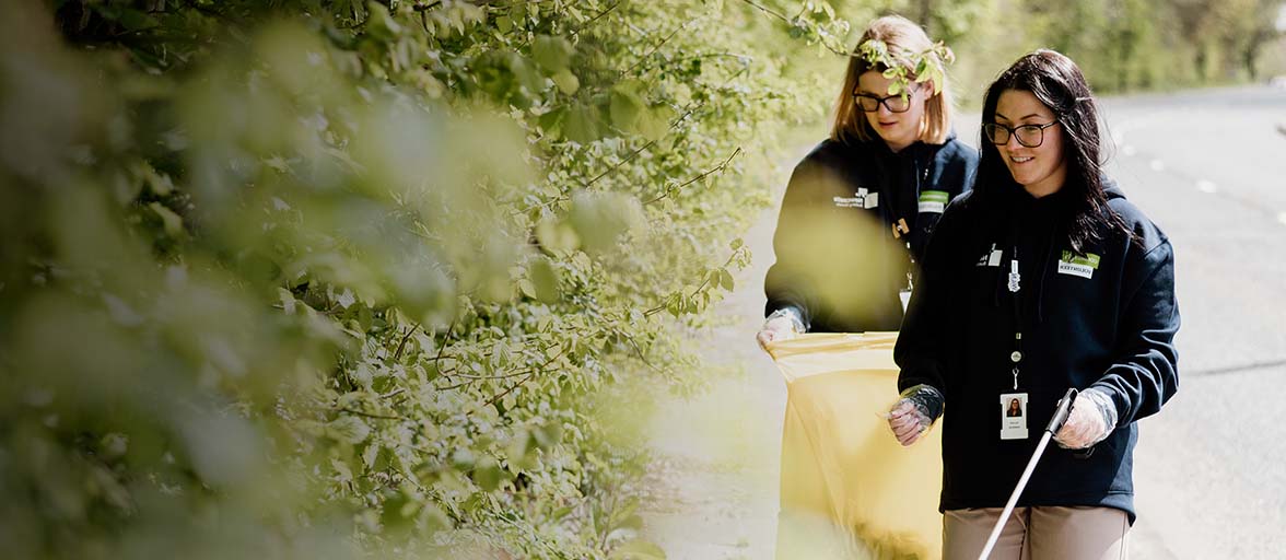Colleagues litter picking by trees and bushes