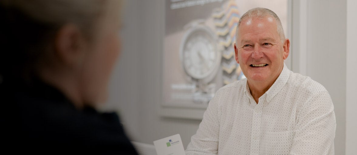 A customer sat in the West Denton branch with a customer assistant, smiling. 