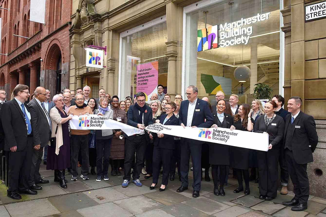 A crowd gathered outside Manchester Building Society as a ribbon is cut during the official opening ceremony.
