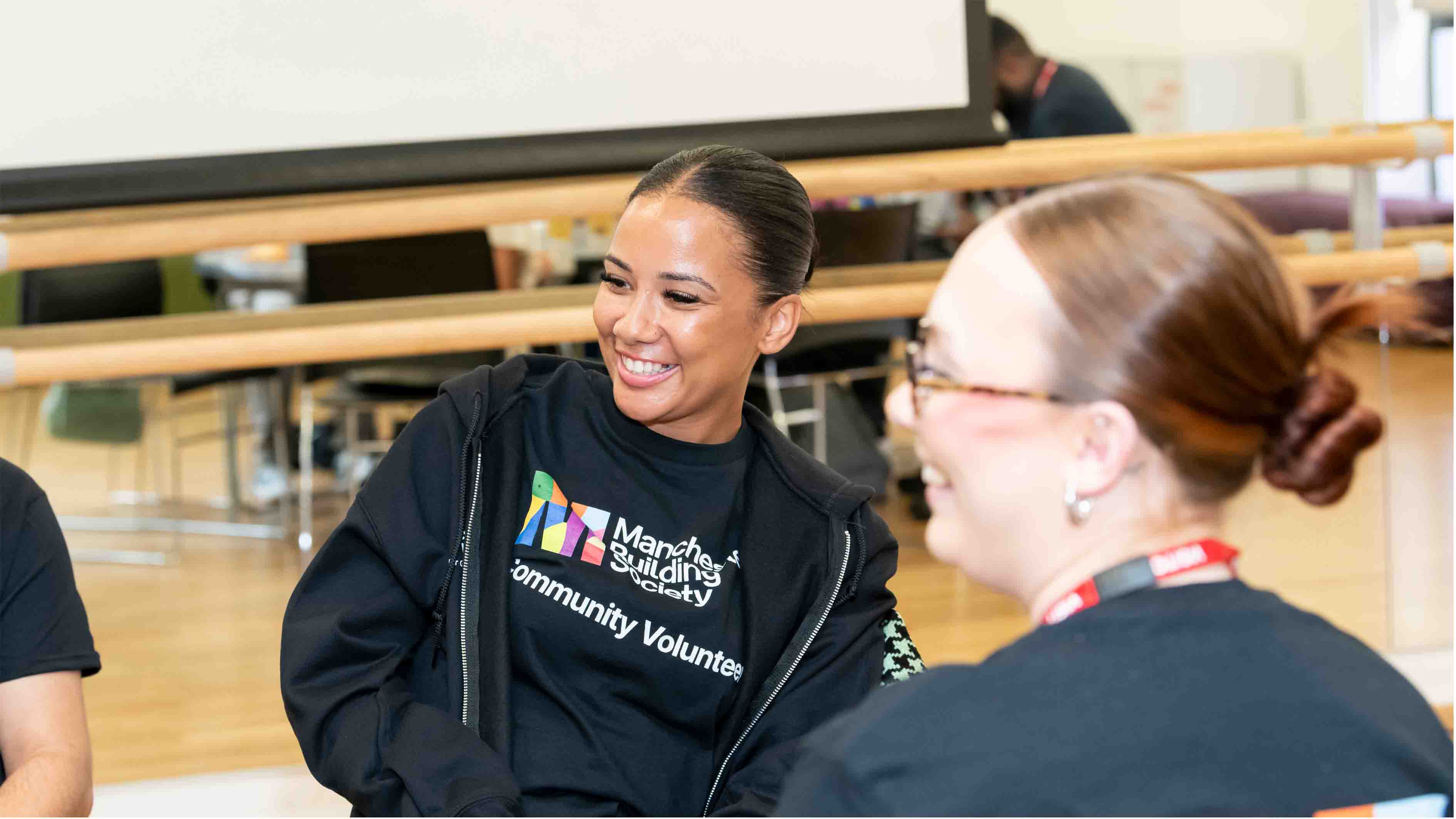 Colleagues wearing volunteering hoodies having a conversation