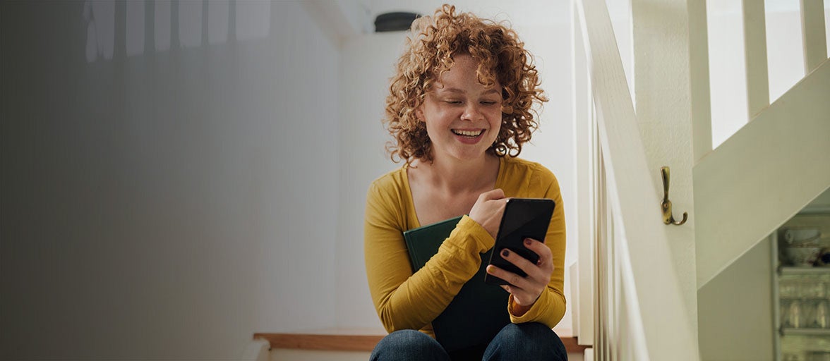 Customer sat on her stairs using a mobile phone