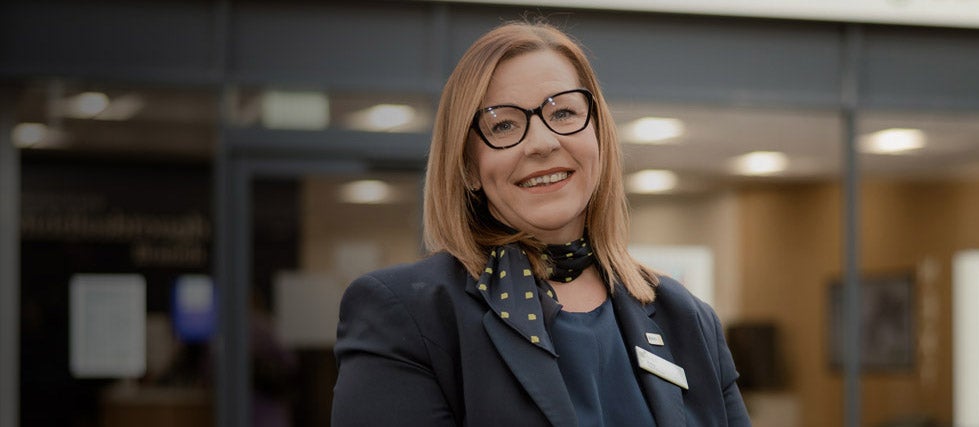 Branch Manager Kelly, stood smiling in front of the branch.