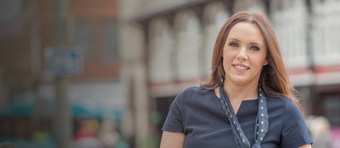 Head and shoulders of a lady stood in front of a busy town center in Darlington. 