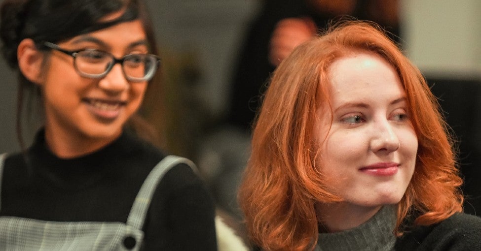 Two young women smile.