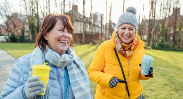 Friends out for a walk while holding coffee cups.