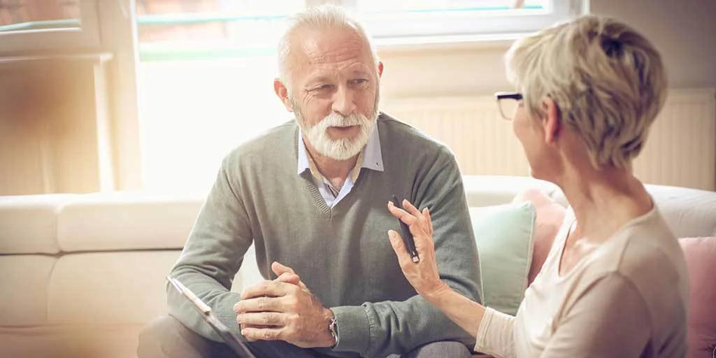 Elderly man with woman discussing his will whilst sitting on the sofa