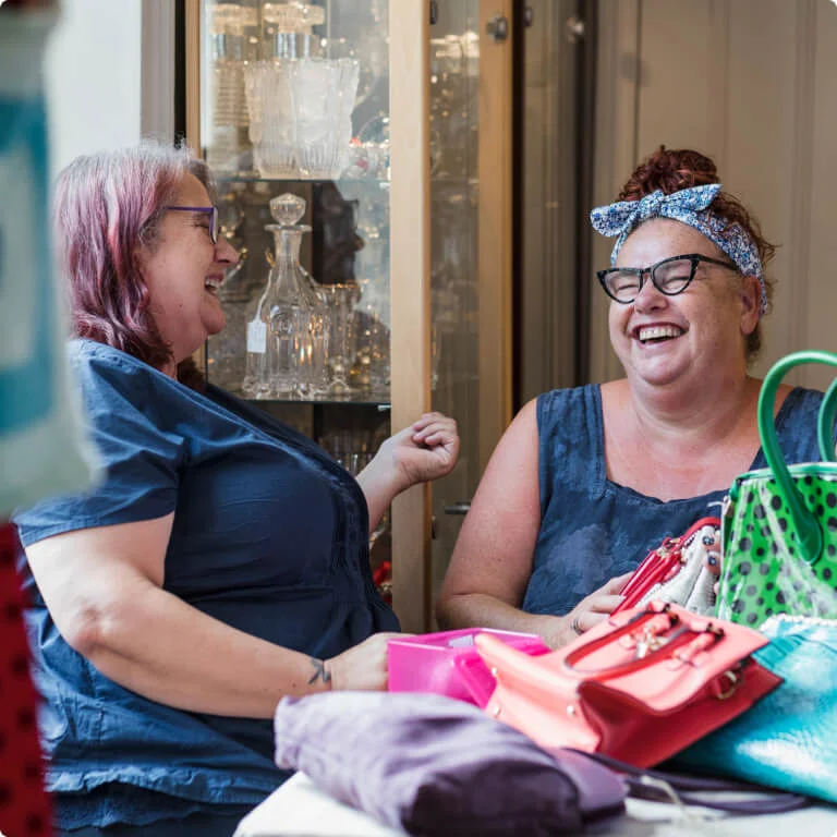 2 friends sitting at a table while laughing to each other.
