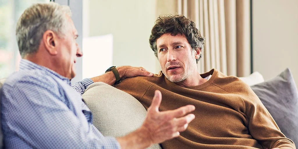 Man and son sitting on sofa as dad discusses his funeral wishes