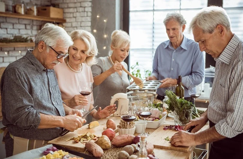 Elderly group of people drinking and preparing dinner in the kitchen