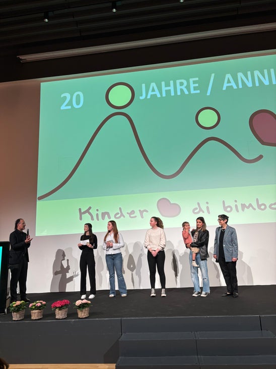 Vorstellung der Sonderedition „Mountain-Rigel mit Herz“ bei der Vollversammlung von Verein Kinderherz im Hotel Sheraton in Bozen am Samstag, 11.04.2026 v. l. n. r. Ulrich Seitz, Präsident – Verein Kinderherz, Lena Pichler, Obfrau der Schülergenossenschaft, Francesca Maria Gentile, Mitglied des Verwaltungsrates, Marion Unterholzner, Koordinatorin der Müsli-Produktion, Melanie Resch mit Tochter, eine Promotorin des Mountain Müslis / Verein Kinderherz – Mitglied und Christine Gutgsell, Koordinatorin der Schülergenossenschaft Foto: FS Tisens
