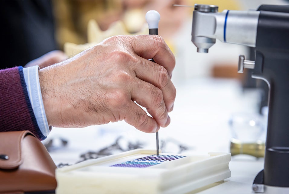 A person using a surgical tool to pick up a CMF plate during a hands-on Materialise Dry Bone training session, with other equipment and instruments visible on the table.