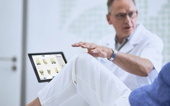 Surgeon speaking to a patient while holding a tablet with 3D planning software