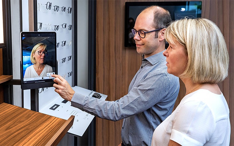 Un ottico professionista e un paziente che utilizzano lo scanner per l'adattamento personalizzato in un centro oculistico