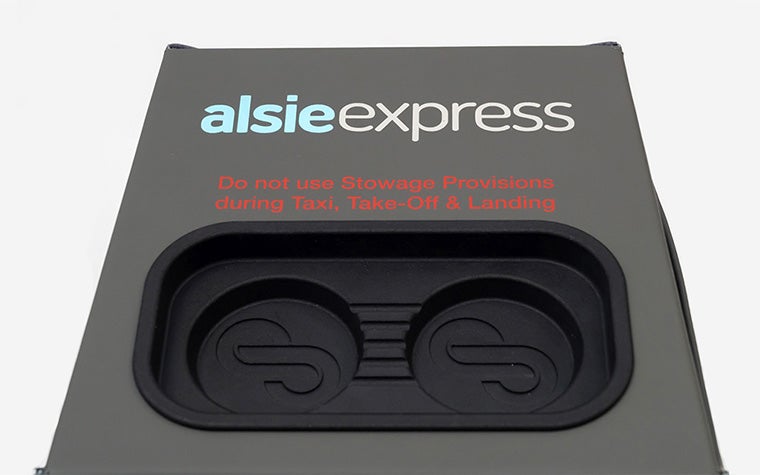 Il sistema occupa-sedile a forma di cubo di Stirling Dynamic, con pelle grigio/verde lavorata a mano e un inserto nero stampato in 3D sul lato superiore per smartphone e altri dispositivi.