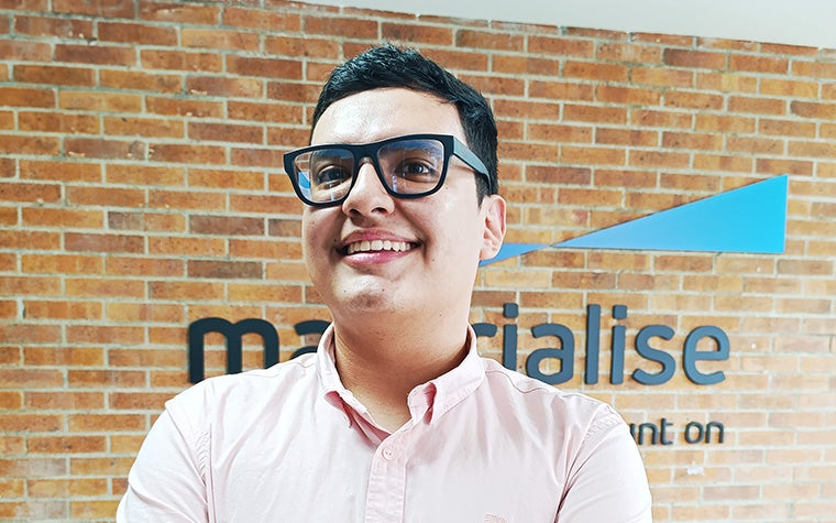 A picture of Sebastián Berrio. He is standing infront of a brick wall with the Materialise logo in the background.