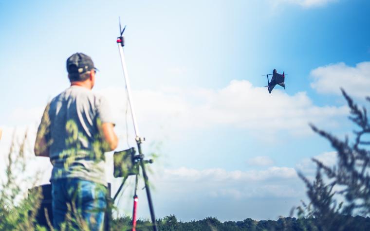 Un hombre con un equipo de topografía sobrevolando un campo abierto con el dron Marlyn Cobalt impreso en 3D.