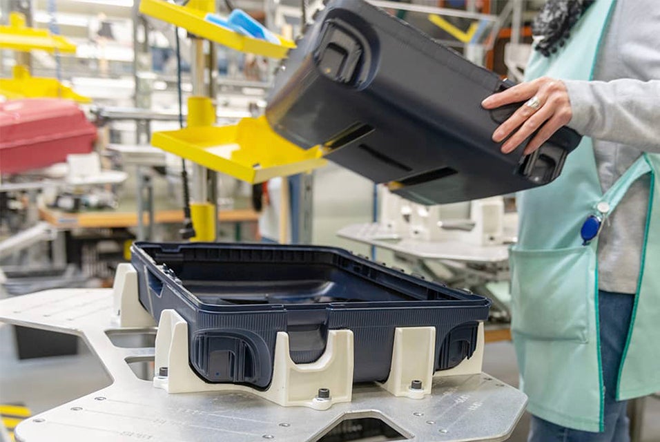 A worker holding half of a suitcase shell