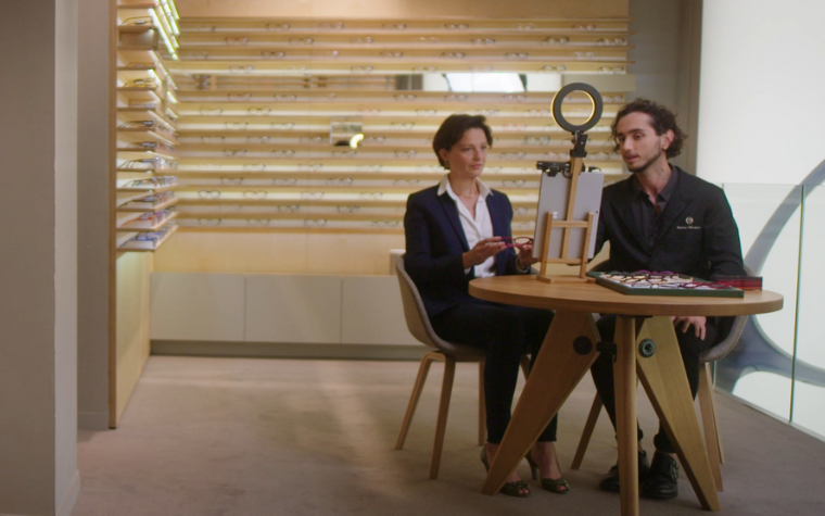 Una donna che utilizza l'Eyewear Fitting Suite al tavolo di un negozio Acuitis, accompagnata da un ottico.