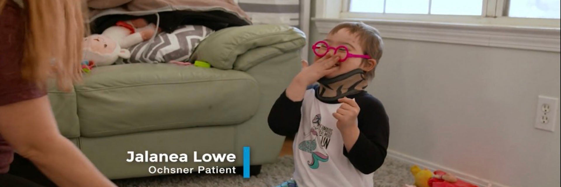 5-year-old Jalanea Lowe sitting on a carpeted floor, surrounded by toys and facing a woman