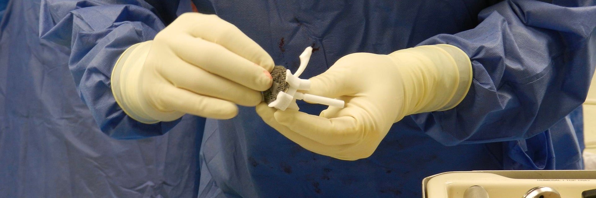 Member of operating theatre team holds Glenius implant and surgical guides 