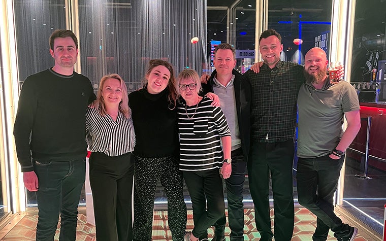 A group photo of three women and four men. They are all smiling at the camera and standing in a line.