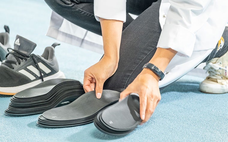 A medical professional picking up a collection of 3D-printed phits orthotics
