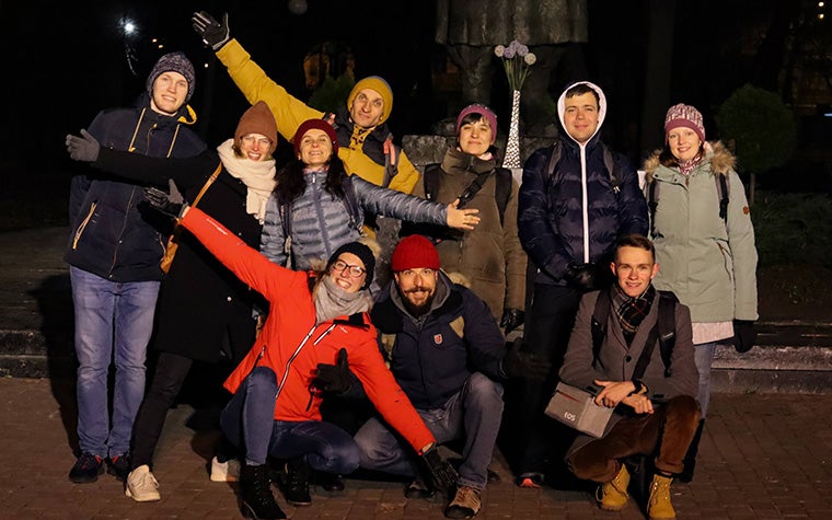 A group photo of the Enlight CMF team standing outside. They are smiling at the camera with their arms open.