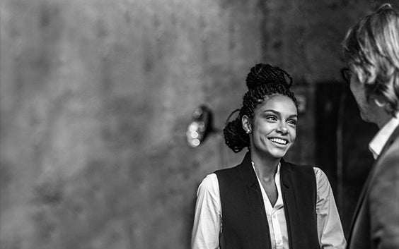 Two women smiling at each other while talking in an open room