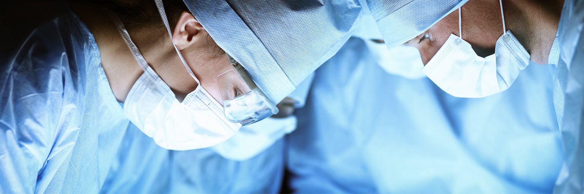 A group of surgeons in surgical gear, looking down