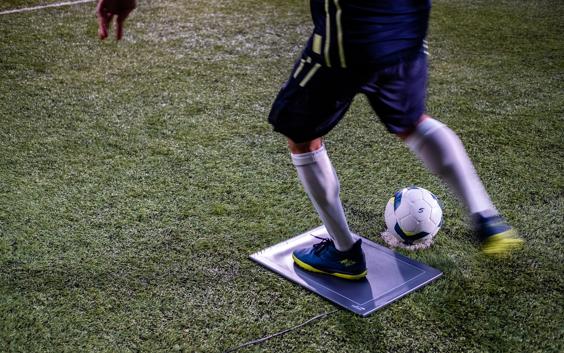 A player running on a pressure plate and striking a soccer ball.