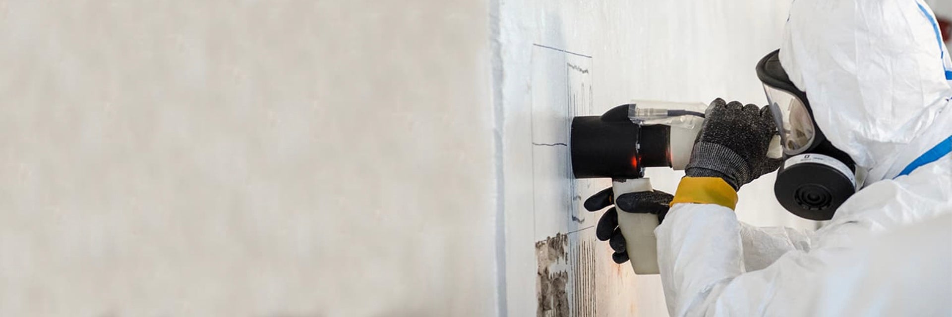 Worker wearing full personal protective equipment uses the ViridiScope to check radiation levels in a wall 