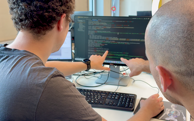 Two men looking at code and pointing at the screen.